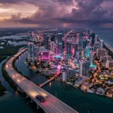 Cinematic aerial view of a Leonida-style coastal city at dusk with wetlands and skyscrapers in the background